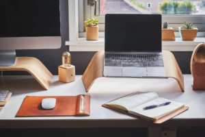 Laptop and Desktop Computers on a desk in front of a home window