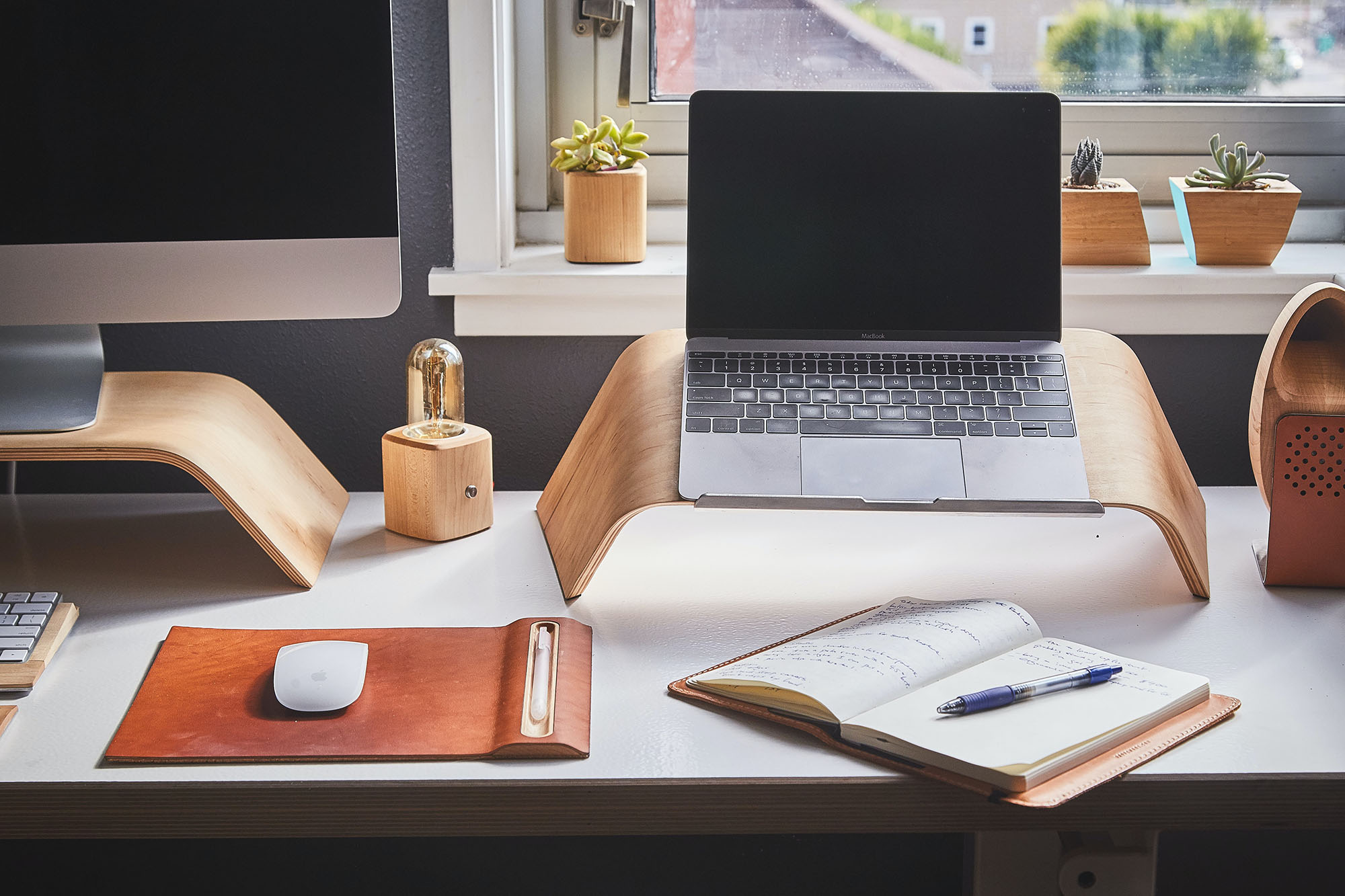 Laptop and Desktop Computers on a desk in front of a home window