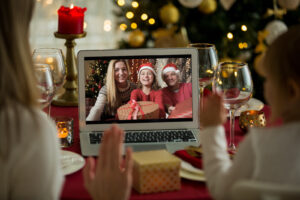 A happy family with a child is celebrating Christmas with their friends on video call using webcam. Family greeting their relatives on Christmas eve online. New normal virtual event