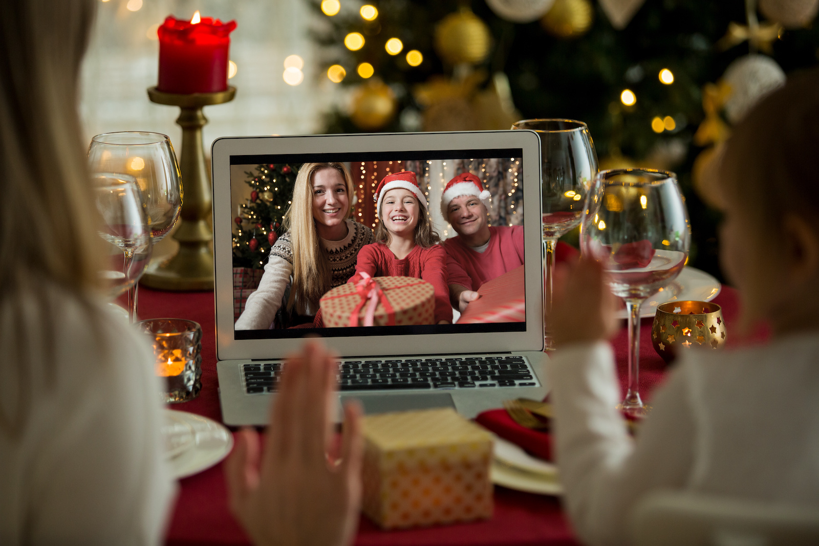 A happy family with a child is celebrating Christmas with their friends on video call using webcam. Family greeting their relatives on Christmas eve online. New normal virtual event