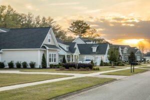 A Street view of a new construction neighborhood with larger landscaped homes and houses with yards and sidewalks taken near sunset