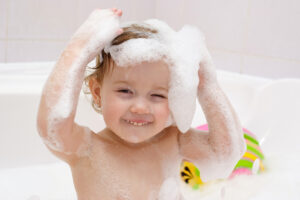 Cute baby is washing her hair in bath